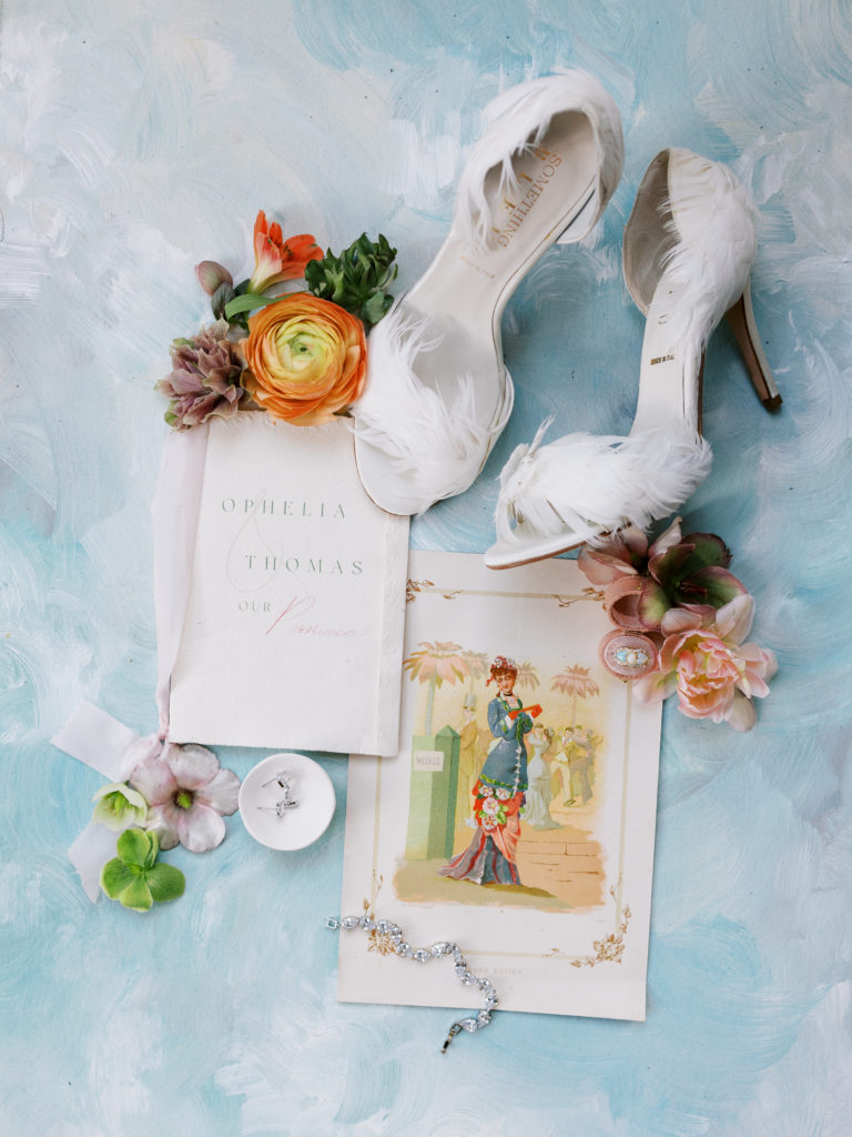 flat lay of bridal details, including vow book and bridal shoes