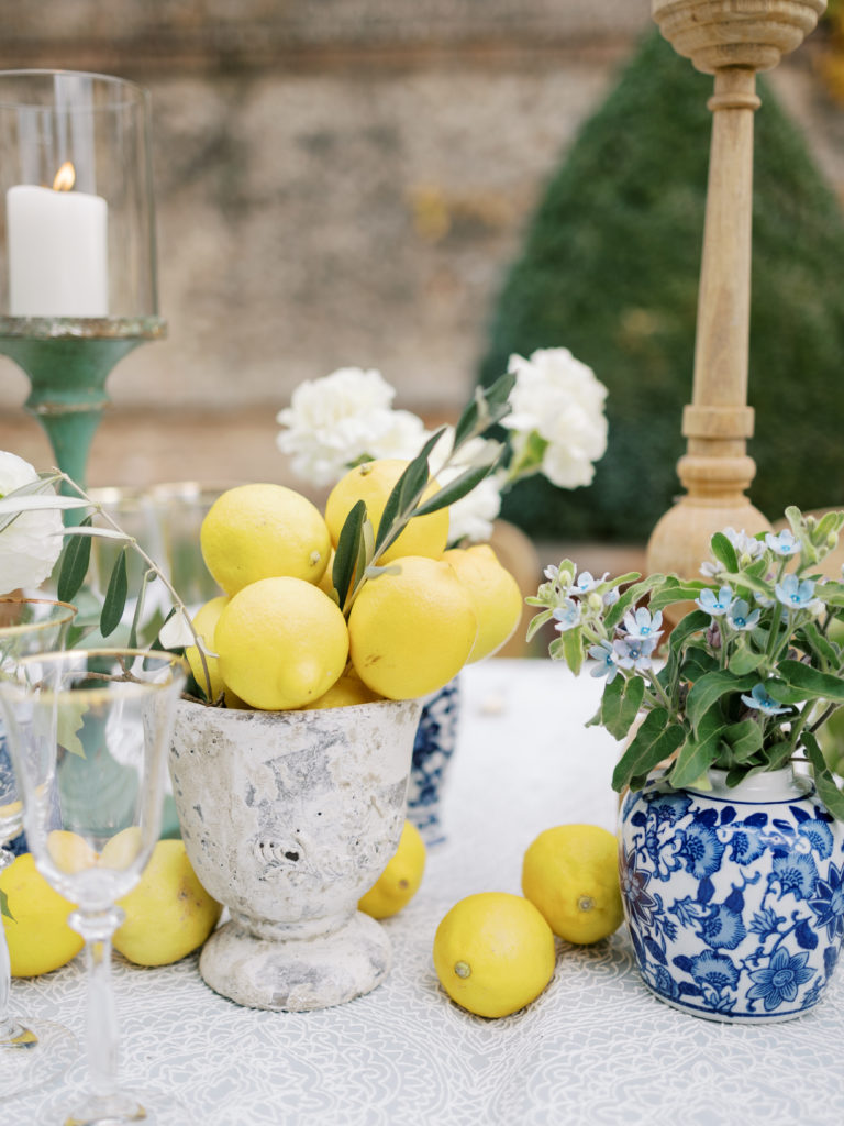 Italian table decor, including blue and white vases, lemons, white florals, and candles