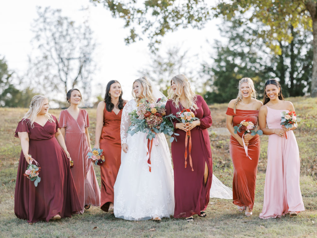 bride and bridesmaids walking and laughing in fall colors